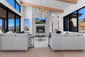 Living room with a large fireplace, hardwood / wood-style floors, beam ceiling, and a towering ceiling