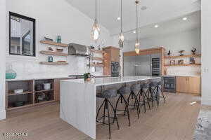 Kitchen with pendant lighting, wine cooler, a breakfast bar area, and an island with sink