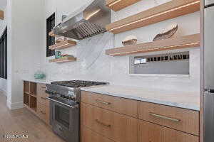 Kitchen featuring high end stainless steel range oven and wall chimney exhaust hood