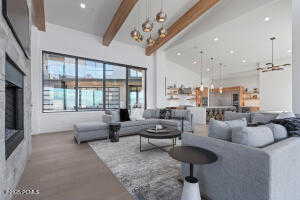 Living room with a notable chandelier, beam ceiling, wood-type flooring, and a high ceiling