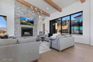 Living room with a large fireplace, beamed ceiling, and light wood-type flooring