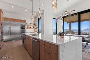 Kitchen with sink, dishwasher, an island with sink, a mountain view, and decorative light fixtures