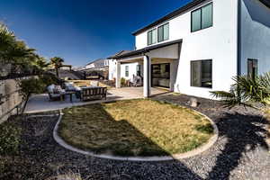 Back of property featuring an outdoor living space, a patio, and a yard