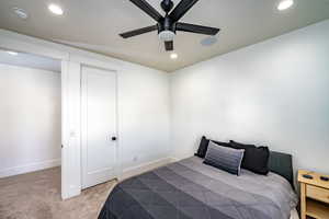 Carpeted bedroom with ceiling fan and a closet