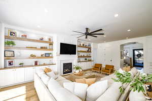 Living room with a brick fireplace, light hardwood / wood-style floors, and ceiling fan