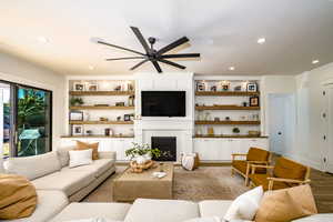 Living room featuring ceiling fan, a fireplace, and light hardwood / wood-style floors