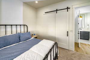 Bedroom featuring ensuite bathroom, a barn door, and sink