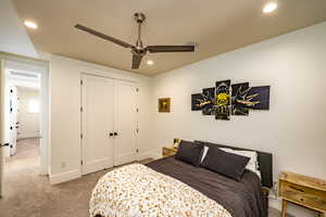 Bedroom with light carpet, ceiling fan, and a closet