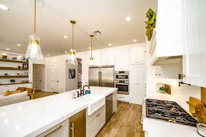 Kitchen featuring pendant lighting, sink, appliances with stainless steel finishes, tasteful backsplash, and white cabinets