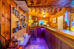 Bar featuring wood ceiling, light hardwood / wood-style flooring, ceiling fan, and wood walls