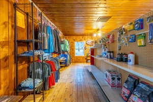 Interior space featuring light wood-type flooring, wooden walls, ceiling fan, and wooden ceiling