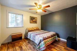 Bedroom featuring ceiling fan, dark wood-type flooring, and a textured ceiling