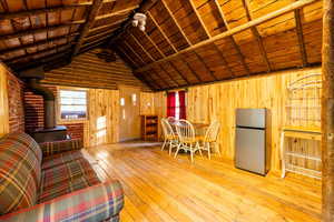 Unfurnished living room featuring a wood stove, wooden walls, and wood ceiling