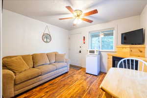 Living room featuring a fireplace, a textured ceiling, hardwood / wood-style flooring, and ceiling fan