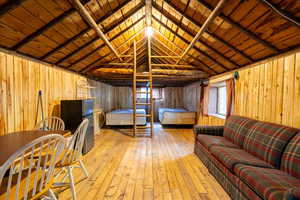 Interior space featuring vaulted ceiling with beams, wood walls, light hardwood / wood-style flooring, and wood ceiling