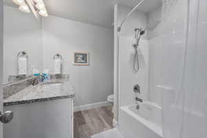 Full bathroom with hardwood / wood-style floors, vanity,  shower combination, toilet, and a textured ceiling