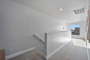 Hallway with carpet flooring and a textured ceiling