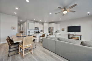 Living room with ceiling fan, sink, and light wood-type flooring