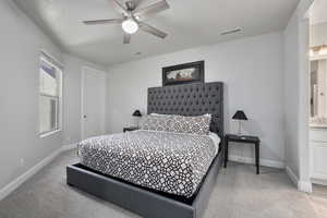 Bedroom featuring light carpet, ceiling fan, and ensuite bathroom