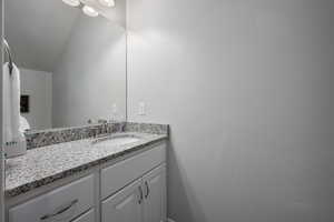 Bathroom featuring lofted ceiling and vanity