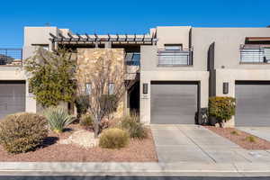 Pueblo-style house featuring a garage and a balcony