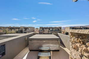 View of patio with a balcony and a hot tub