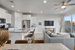 Kitchen with sink, light stone counters, a kitchen breakfast bar, stainless steel appliances, and white cabinets