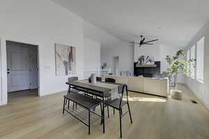 Dining space featuring high vaulted ceiling, ceiling fan, and light hardwood / wood-style flooring