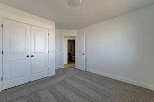 Unfurnished bedroom featuring light carpet and a closet