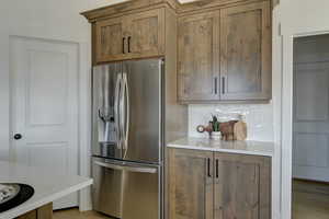 Kitchen with tasteful backsplash, stainless steel fridge, and light wood-type flooring