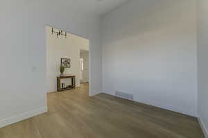 Spare room featuring a towering ceiling and wood-type flooring