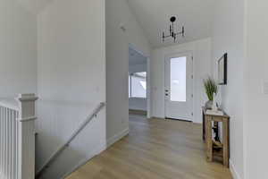 Foyer featuring light hardwood / wood-style floors, lofted ceiling, and a chandelier