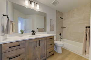 Full bathroom featuring toilet, vanity, tiled shower / bath, and wood-type flooring