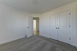 Unfurnished bedroom featuring a closet and light colored carpet