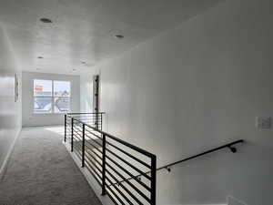 Stairs with baseboards, carpet floors, and a textured ceiling