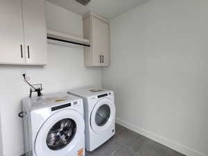 Washroom featuring baseboards, cabinet space, visible vents, and washing machine and clothes dryer