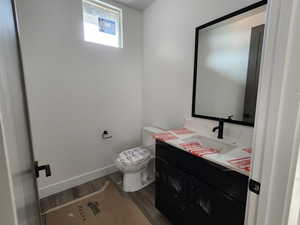 Bathroom featuring vanity, toilet, wood finished floors, and baseboards