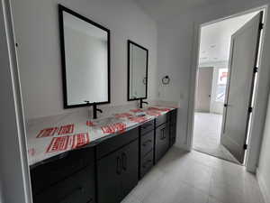 Jack and Jill bathroom with double vanity, tile patterned flooring, and a sink