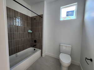 Jack and Jill bathroom featuring bathtub / shower combination, toilet, and baseboards