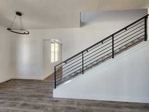 Stairway featuring wood finished floors, a textured ceiling, and baseboards