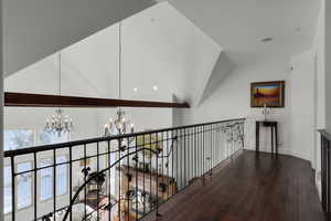 Corridor with hardwood / wood-style flooring, a chandelier, and lofted ceiling