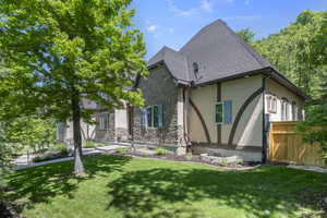 View of front of house with stone siding, stucco siding, and a front yard