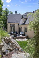 Back of property with an outdoor living space, stucco siding, a chimney, and roof with shingles