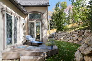 Property entrance with roof with shingles, stucco siding, and a deck