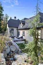 Rear view of property featuring an outdoor living space, stucco siding, a chimney, and a shingled roof