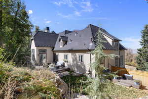 Back of property with a wooden deck, stucco siding, outdoor lounge area, and a chimney