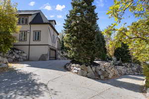 View of property exterior featuring stucco siding, stone siding, and concrete driveway