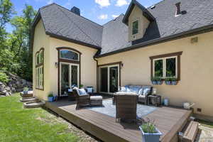 Back of property featuring an outdoor hangout area, stucco siding, a deck, and a yard