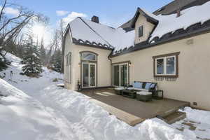 Snow covered rear of property with a deck