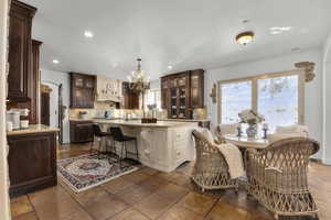 Kitchen featuring a center island, tasteful backsplash, a kitchen breakfast bar, hanging light fixtures, and a chandelier